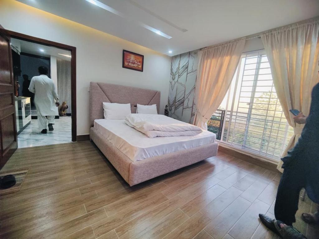 a bedroom with a bed and a man walking in the doorway at Snow Stones in Khaira Gali