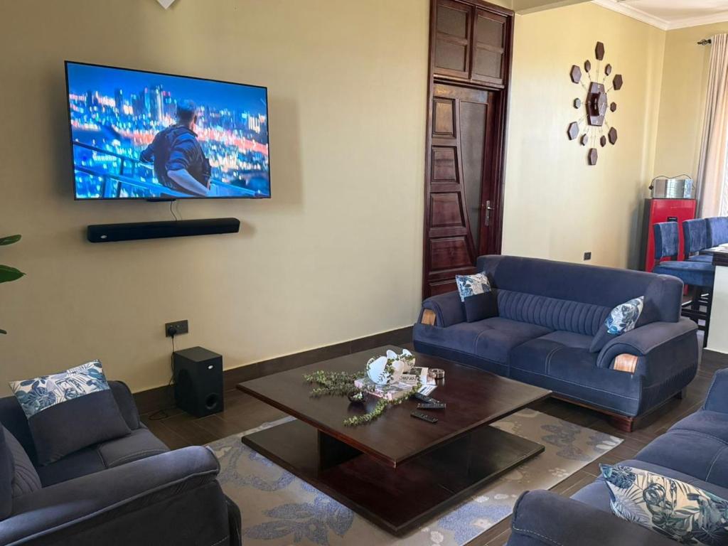 a living room with two blue couches and a coffee table at Nady Apartment in Dodoma