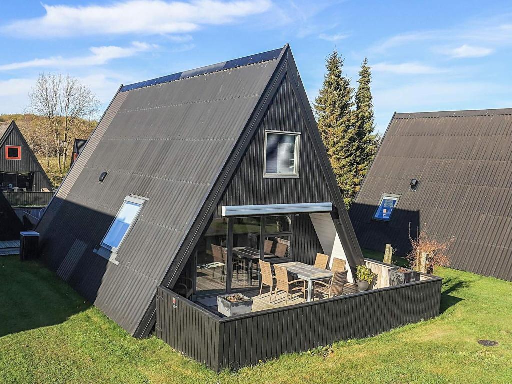 a black barn with a table and chairs in a yard at Himmerland Stay, Golf & Spa in Farsø