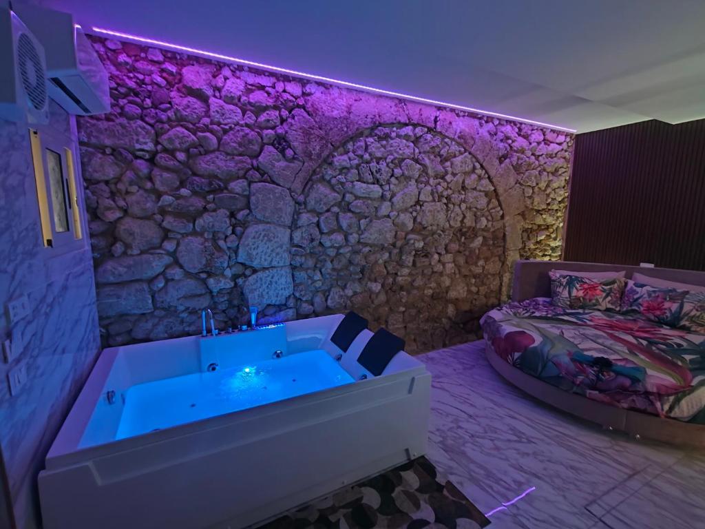 a bathroom with a tub and a stone wall at Suite San Giovanni in Gela