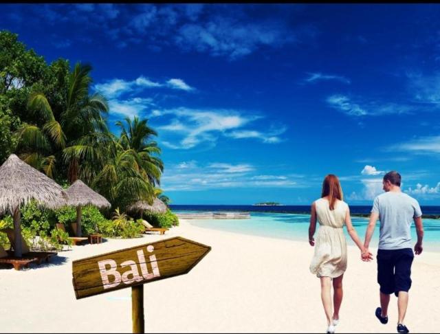 un hombre y una mujer caminando en una playa con un cartel de pelota en Tanjung Sari Inn en Nusa Dua