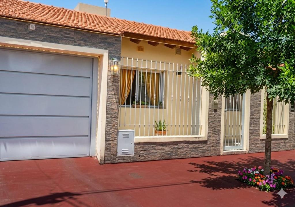 a house with a garage door and a tree at Casa Premium con Cochera en Mendoza Ideal Familias Hasta 7 pers in Mendoza