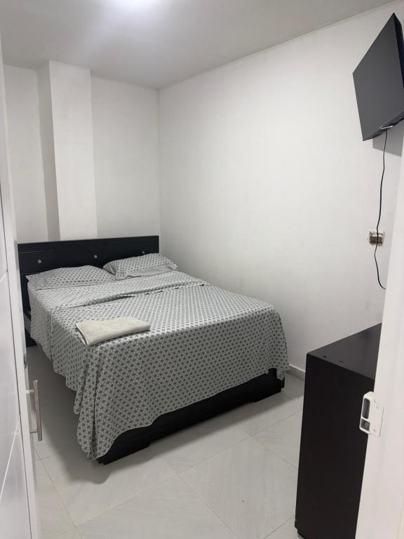 a small bedroom with a bed and a television at Hotel Azulado - Como el mar in Jamundí