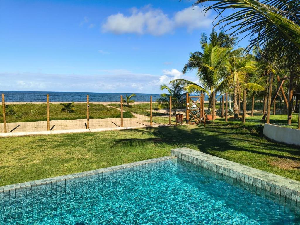 a swimming pool with a view of the ocean at Pé na areia, 3 suítes, terraço com piscina privativa in Camacari