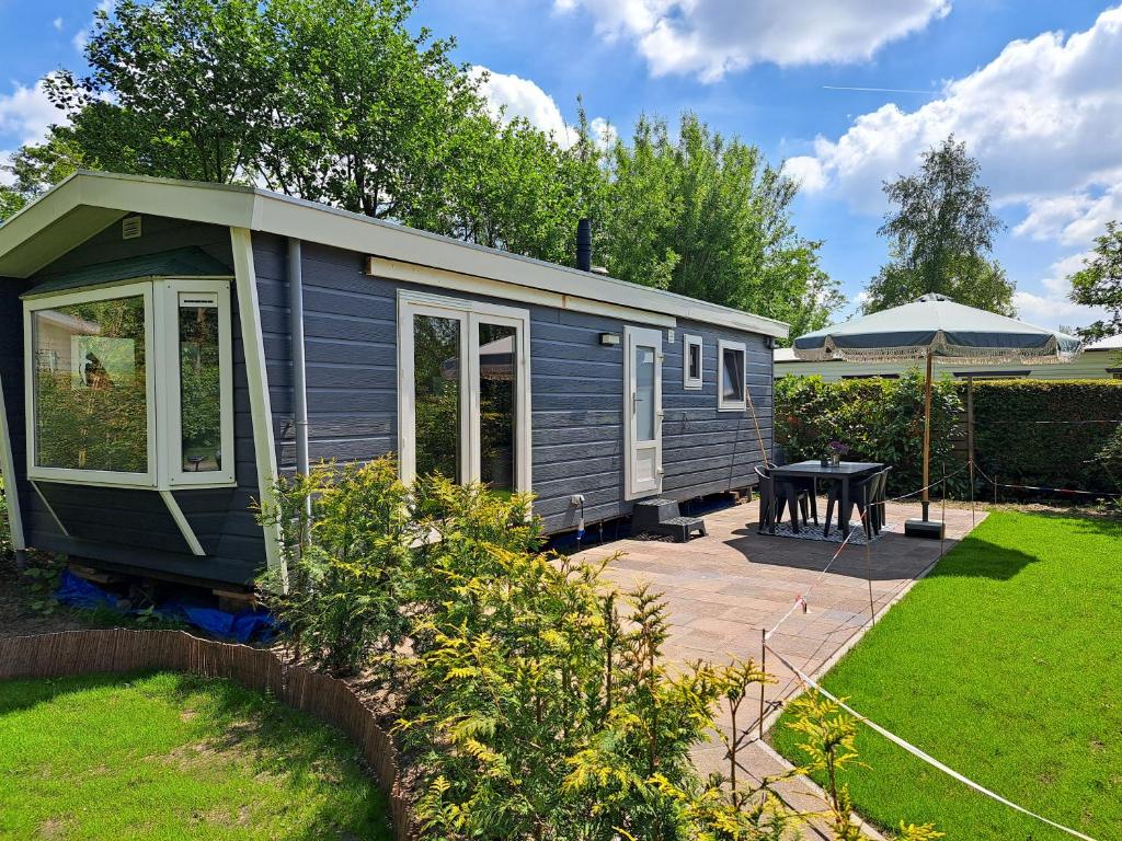 a blue tiny house in a garden with a patio at Camping de Zandhorst, Chalet Madera in Wouterswoude