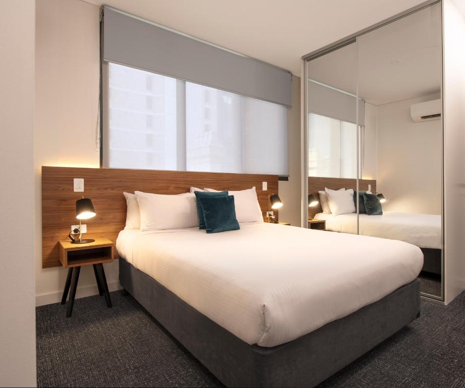a bedroom with a large bed and a mirror at Durham Serviced Apartments in Adelaide