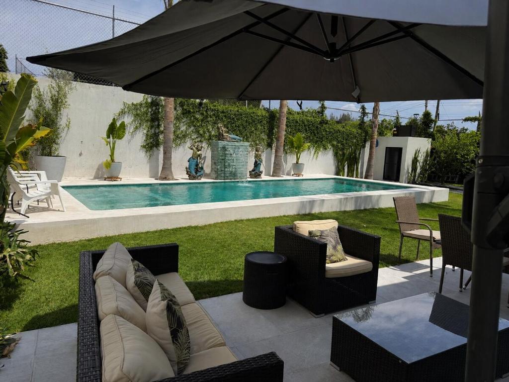a patio with an umbrella and chairs and a pool at Casa Lomas Guadalajara Jalisco in Lomas de Santa Anita
