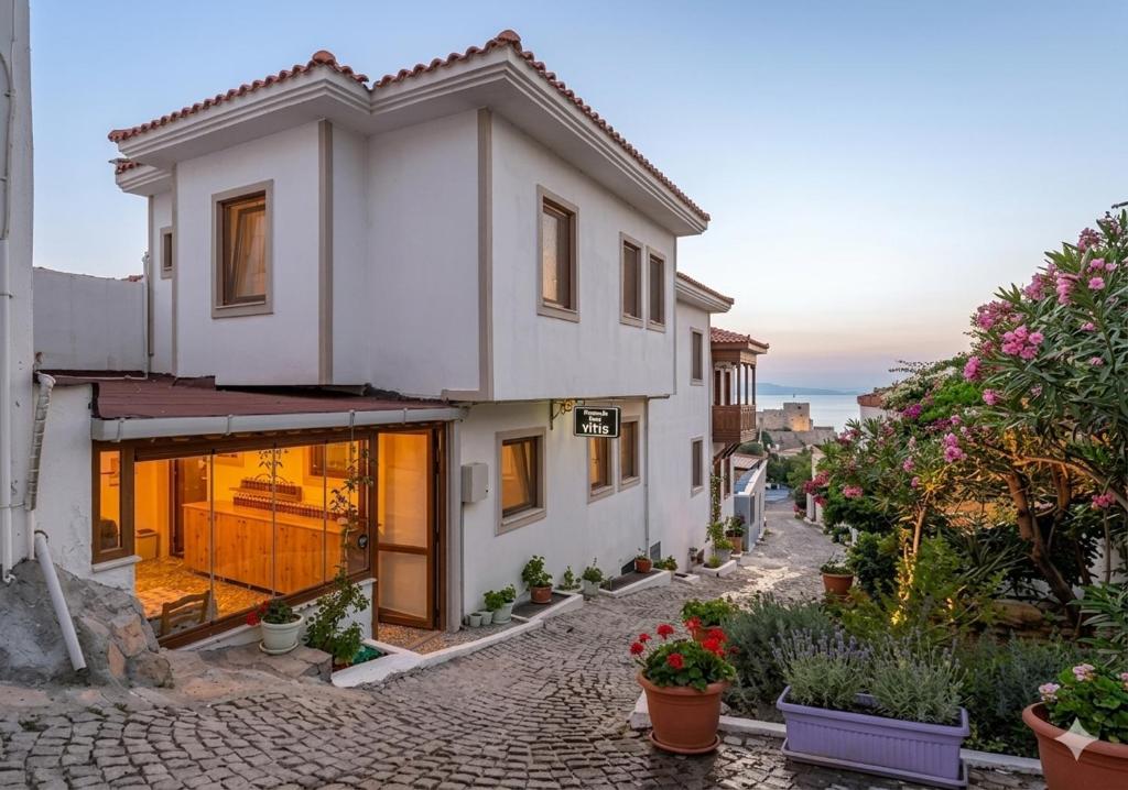 ein weißes Haus in einer Straße mit Topfpflanzen in der Unterkunft Bozcaada Vitis Hotel in Bozcaada
