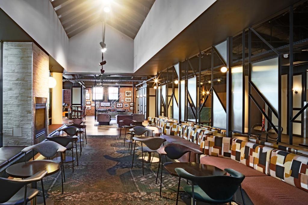 a room with chairs and tables and windows at Amora Herencia Riverwalk Melbourne in Melbourne
