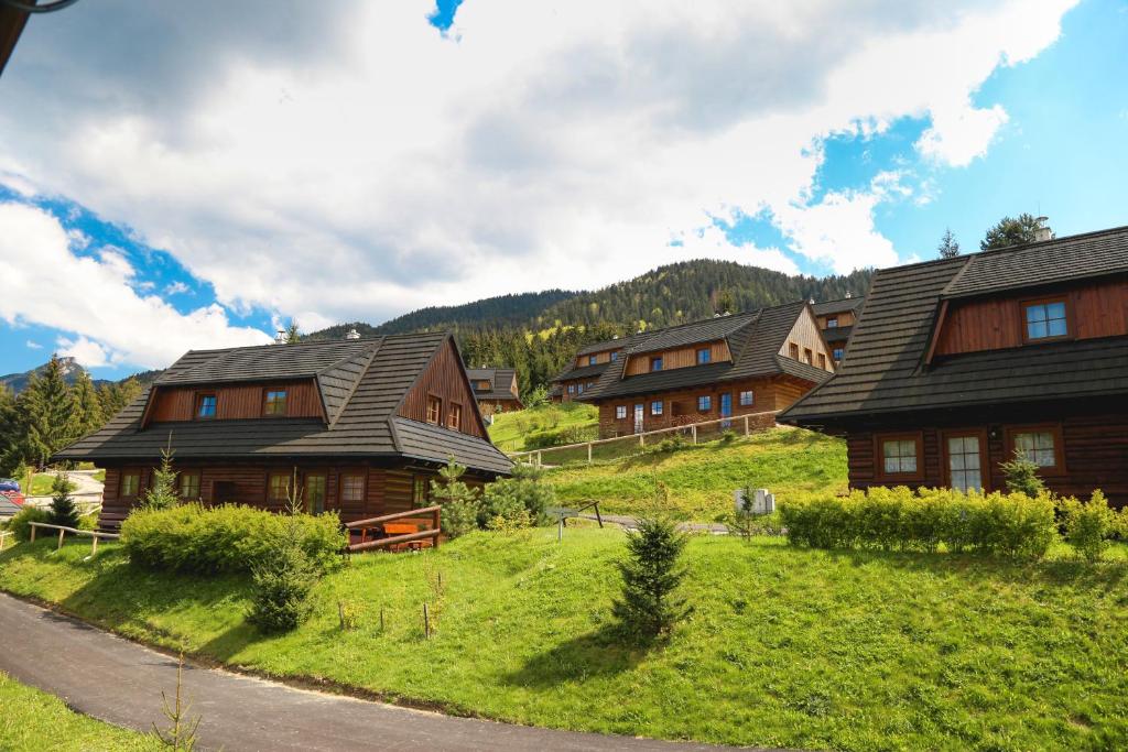 a group of wooden houses on a grassy hill at Drevenica Desina in Terchová