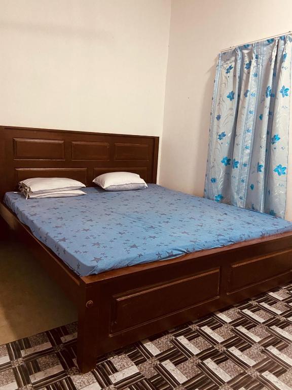 a bed with a wooden frame and blue sheets and pillows at KR Villa in Arugam Bay