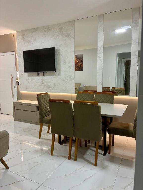 a dining room with a table and chairs and a tv at Apto novo prox Parque Thermal e centro de evento in Piratuba