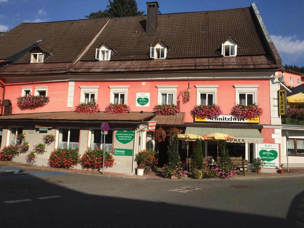 a pink building with flowers in front of it at Bed & Breakfast Goldener Stiefel in Mariazell