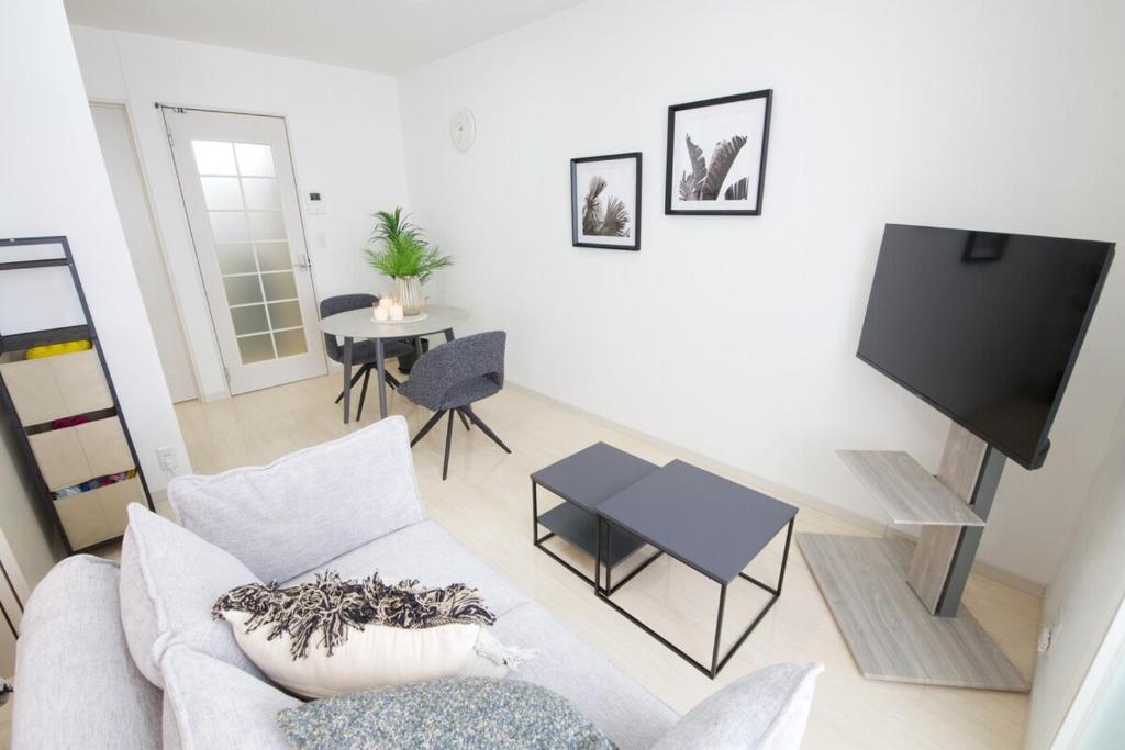 a living room with a couch and a tv at Green Gables B棟 108 in Toyama