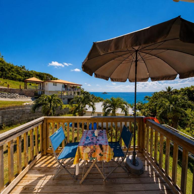 a table and chairs on a deck with an umbrella at Studio bord de mer Home Dominik in Le Robert