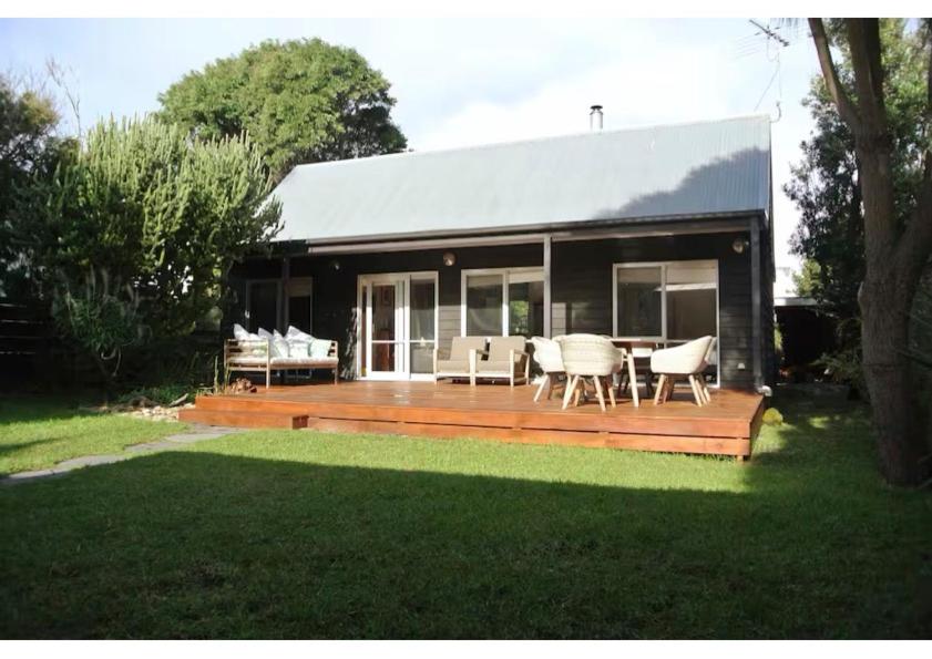 a house with a deck with a table and chairs at Clambake Beach House in Cape Woolamai