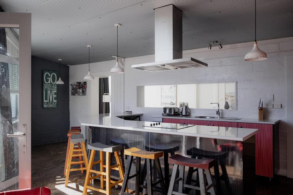 a kitchen with a counter with stools in it at Ruby SoHo Workshop Villa in Port Sorell