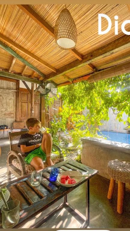 a young boy sitting on a chair in a patio at Villatik in Timuran