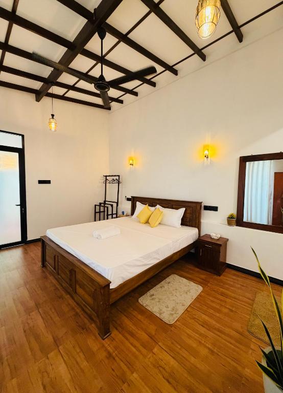 a bedroom with a large bed with white sheets and wooden floors at Earthora Escape in Dickwella