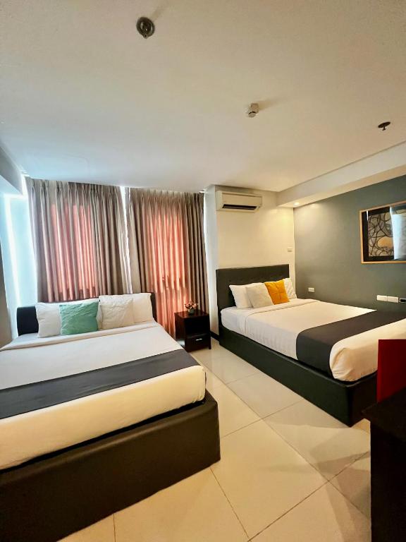 a hotel room with two beds and a window at The Upperhouse Hotel Boutique Stay with City & River Views in Cagayan de Oro