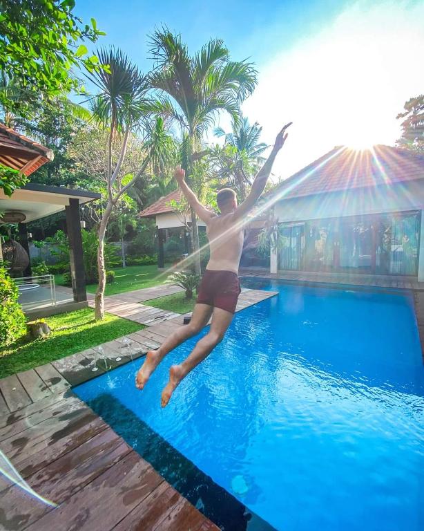 a man jumping into a swimming pool at Coco Garden Pool Villas in Kubutambahan