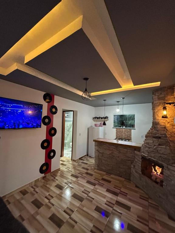 a living room with a stone fireplace and a blue aquarium at Catavento in Paty do Alferes