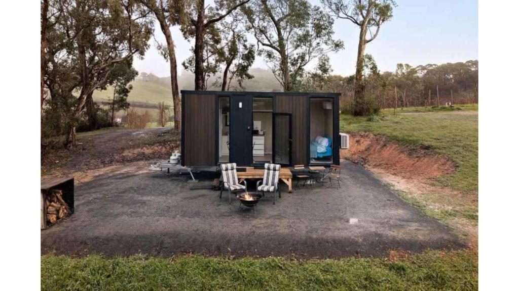 a tiny house with a table and chairs in a field at Churinga Orchards by Tiny Away in Lenswood