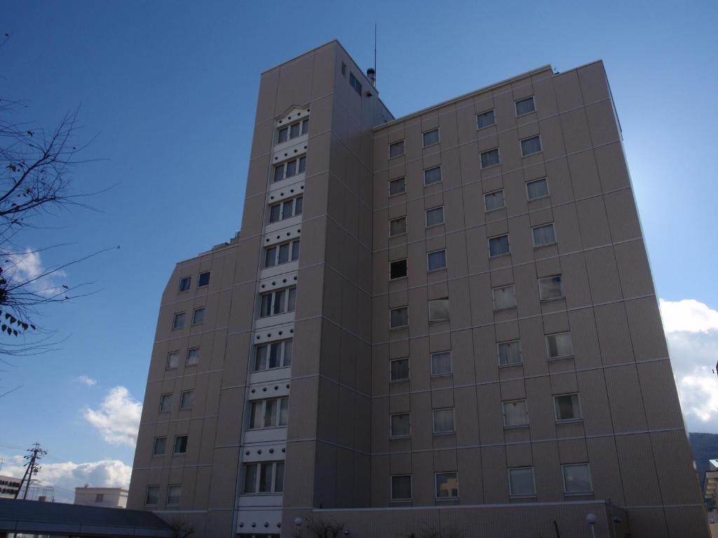 a tall building with a blue sky in the background at Hotel Crown Hills Okaya in Okaya