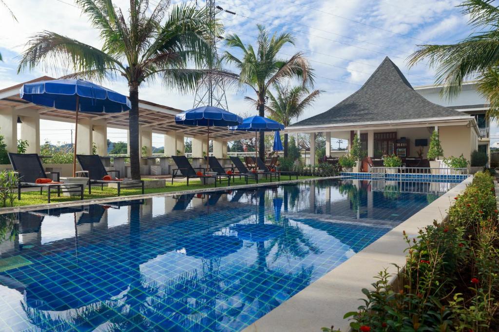 a swimming pool with chairs and umbrellas next to a house at Impress Resort in Thalang