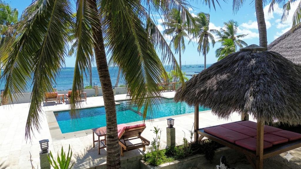 a resort with a swimming pool and palm trees at Belar Reef Bungalows in Nembrala