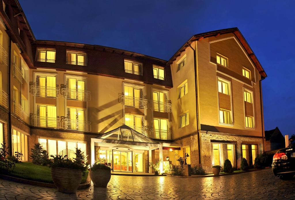 un gran edificio con sus luces encendidas por la noche en Hotel Citrin - Adults Only en Brasov