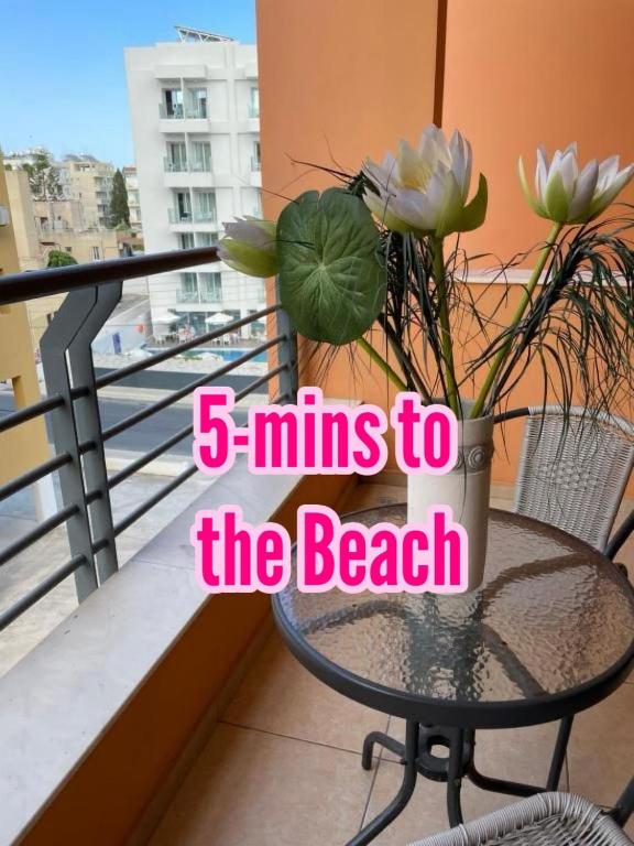a table with a vase with flowers on a balcony at VIP Resort Apartment on Makenzie Beach in Larnaca