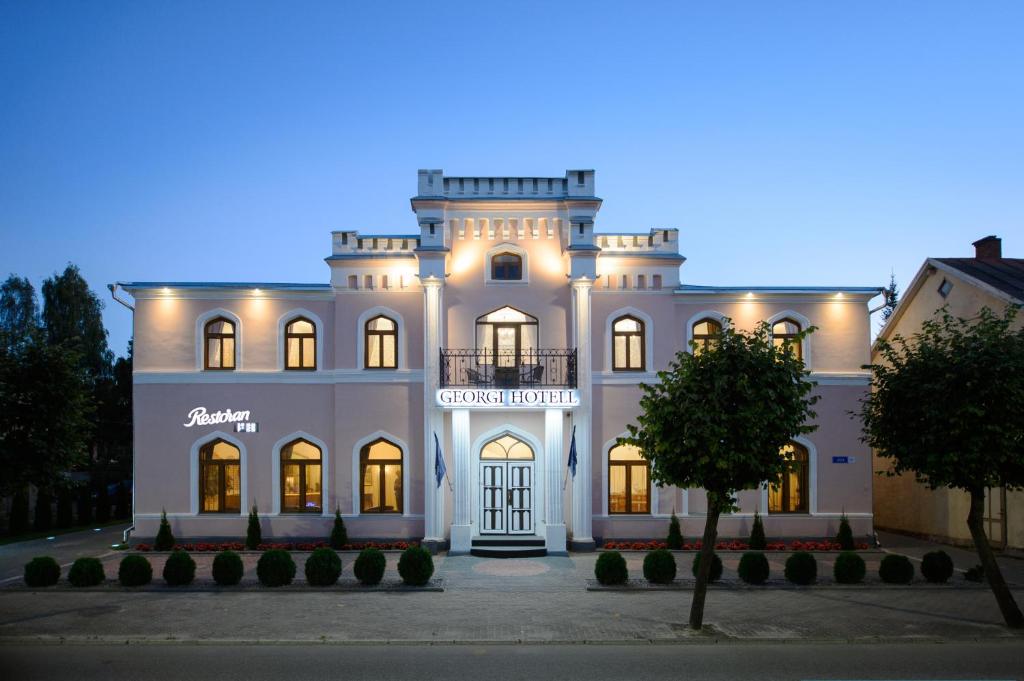 un gran edificio blanco con luces encendidas en Georgi Hotell en Võru