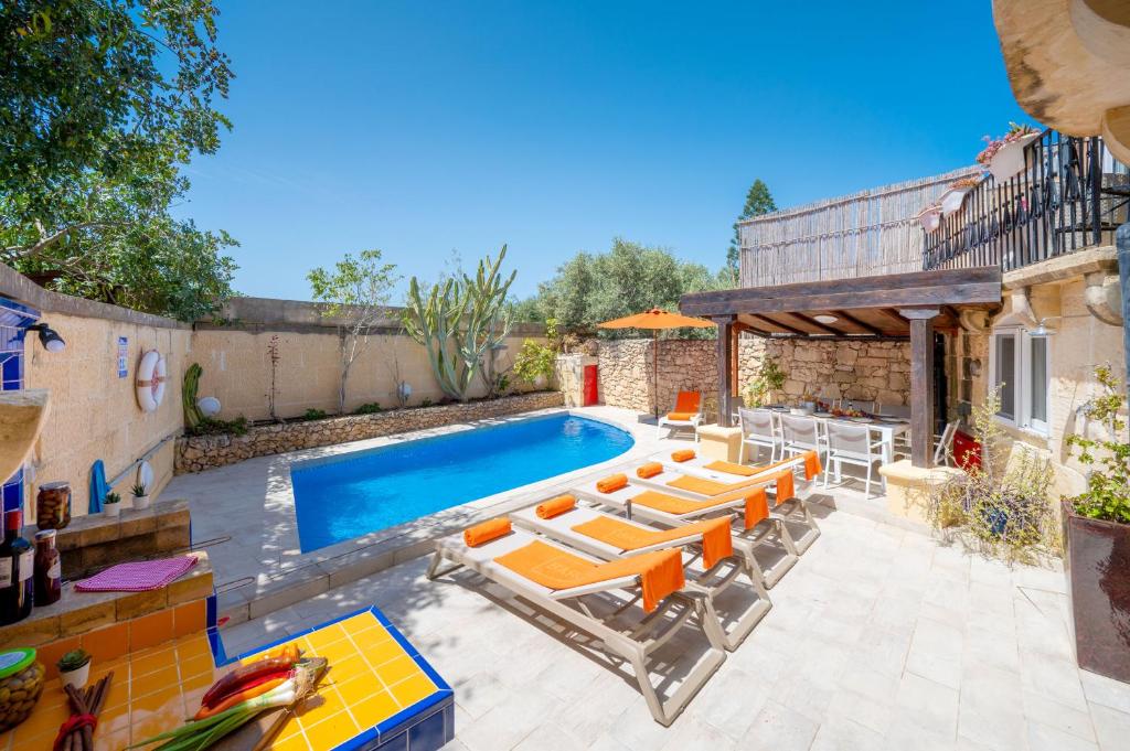 a pool with lounge chairs and a swimming pool at Il-Mohba Holiday Home in Munxar