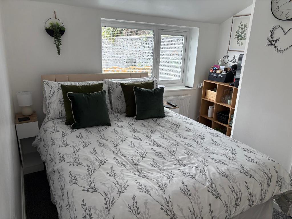 a bedroom with a bed with green pillows and a window at The Snug Guestroom Poole in Poole