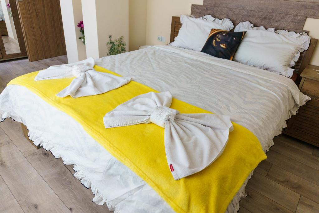 a bed with yellow and white sheets and bows at Desitas home in Plovdiv