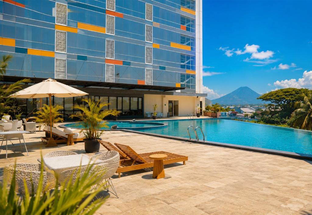 a swimming pool with chairs and a building at Ascent Premiere Hotel and Convention in Malang