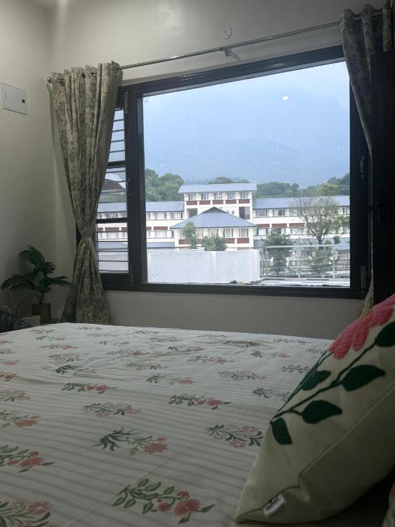 a bedroom with a bed and a large window at Cloud & Calm Homestay in Dharmsāla
