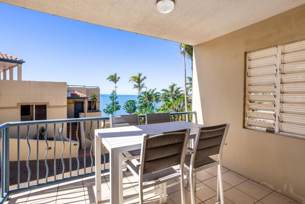 a balcony with a table and chairs and a view of the ocean at Eight, Villa Mar Colina in Yeppoon
