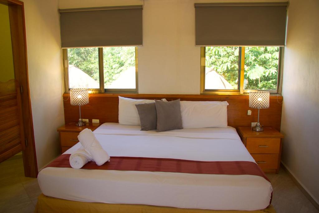 a bedroom with a large white bed with two windows at Hotel Scarlette in Tulum