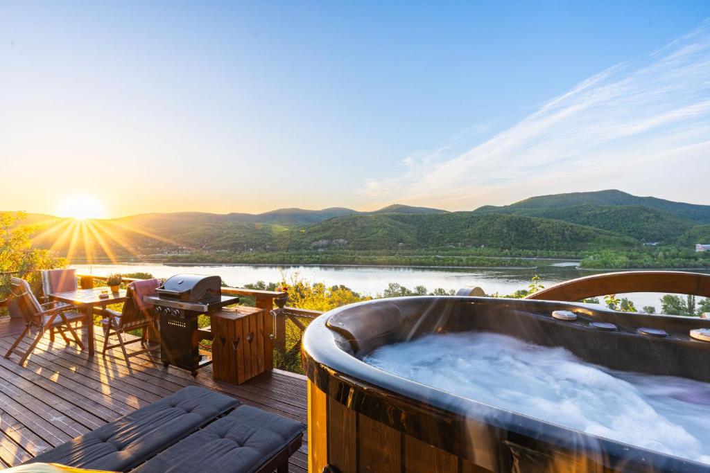a hot tub on a deck with a view of a river at Sherpa Pihenőház in Nagymaros