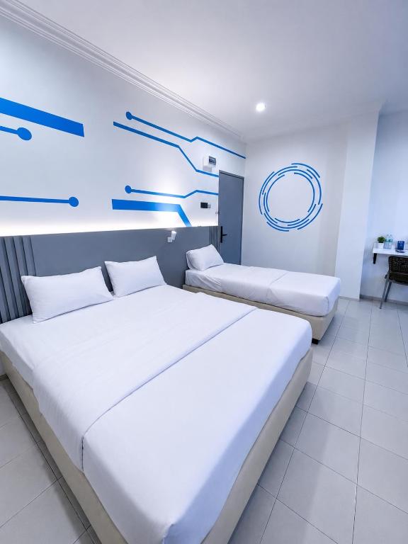 two beds in a room with blue arrows on the wall at One Stop Hotel Ipoh in Ipoh