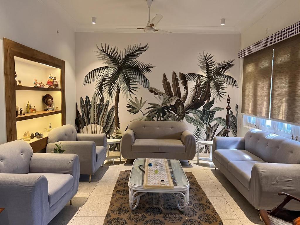 a living room with couches and palm trees on the wall at Cozy Loft 201 2 BHK in Jaipur