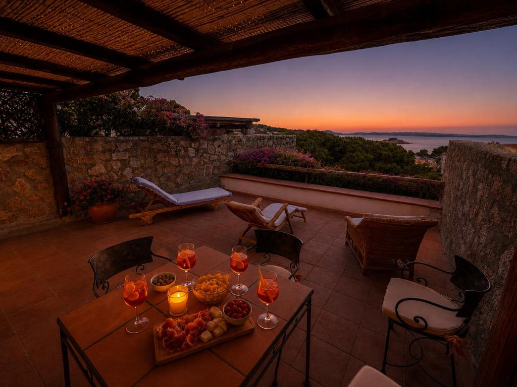 a table with wine glasses on top of a patio at Amazing Sea View Terrace A with Pool 70m from the Beach in Baja Sardinia