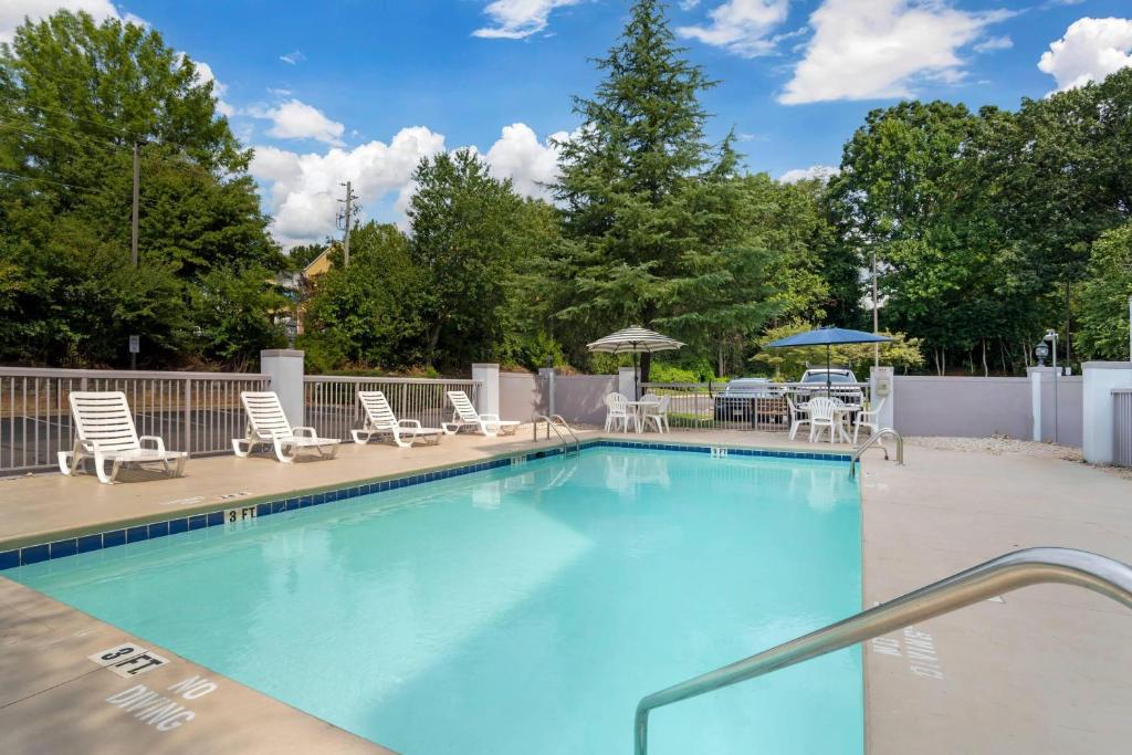 a large swimming pool with chairs and umbrellas at Comfort Suites Gastonia - Charlotte in Gastonia