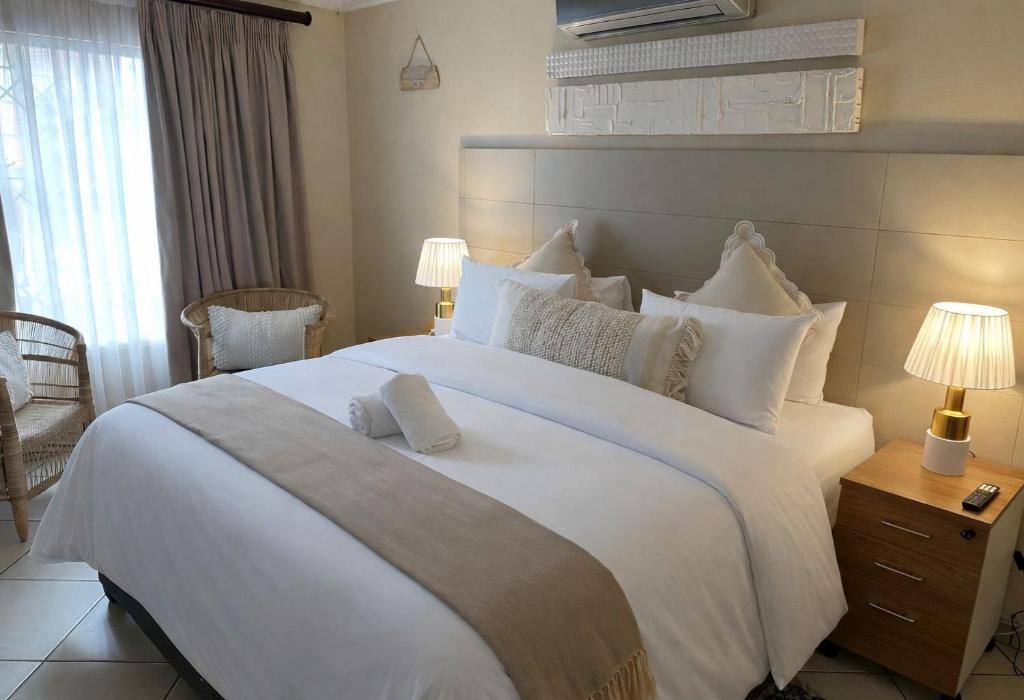 ein Schlafzimmer mit einem großen weißen Bett und weißen Kissen in der Unterkunft Koi liv-Inn Bedfordview ll Modern Guest House Near OR Tambo in Bedfordview