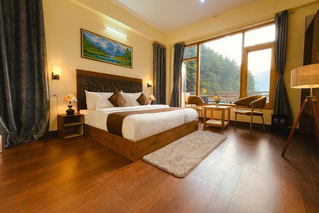 a hotel room with a bed and a large window at Hotel The Winterline - Best Selling Property in Kasol 2025-26 in Kasol