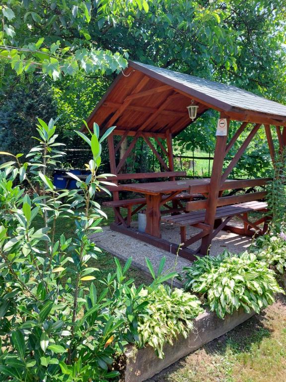 a wooden picnic table with a roof in a garden at Aranymoha Vendégház in Szőce
