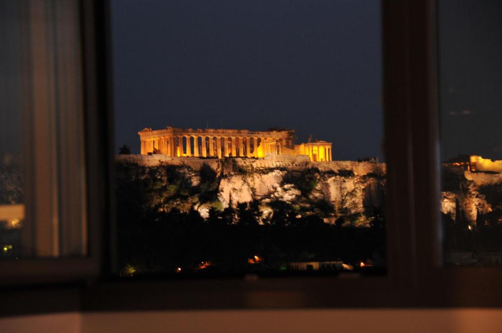 una vista de la acrópolis por la noche desde una ventana en Acropolis at Home: Loft with a View, en Atenas