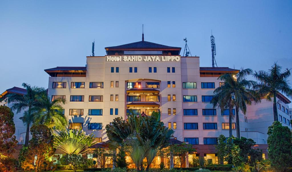 a hotel building with palm trees in front of it at Hotel Sahid Jaya Lippo Cikarang in Cikarang
